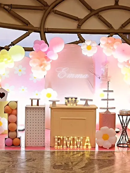 A fresh and sweet daisy theme for Emma's first birthday. This lovely setup features a pastel pink and yellow color palette, daisy flower cutouts, and a cute dessert cart.