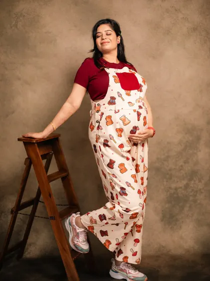 A fun and casual studio look with cute overalls. This shows that maternity shoots can be playful and reflect your personal style.