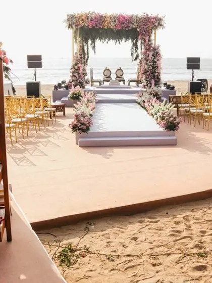 A wider view of the Goa beach wedding setup. This shot shows the guest seating, the aisle, and a charming welcome stand with cones of petals, illustrating how I plan the entire guest experience.