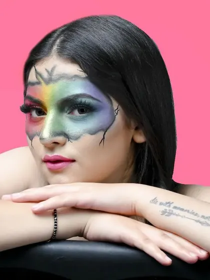 A close-up, expressive portrait that highlights the intricate details of the face paint and the model's tattoo, adding a personal touch to the creative shot.
