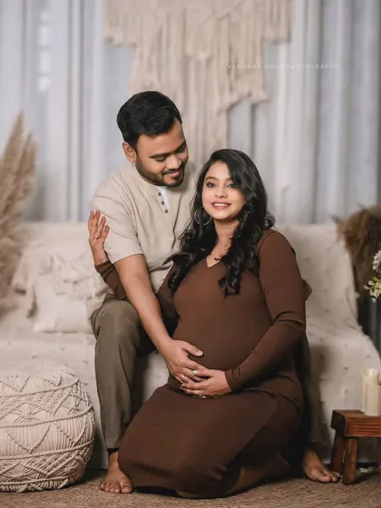 A loving couple poses in a warm, bohemian-inspired studio. The earthy brown tones and natural textures create a cozy and intimate atmosphere.