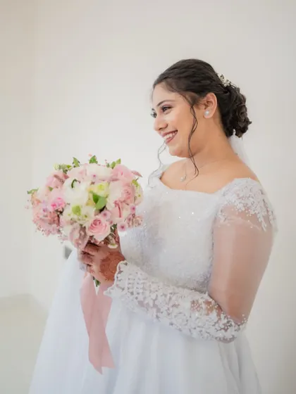 A happy, smiling portrait of the bride in her white wedding gown, holding her bouquet.