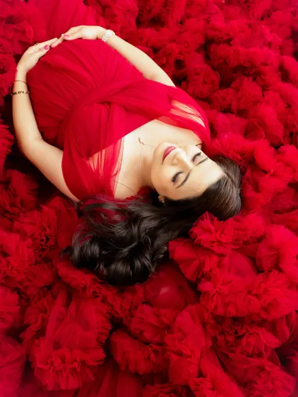 A dreamy overhead shot of a mama-to-be lying in a sea of red tulle. This artistic angle creates a beautiful and dramatic portrait that feels like a painting.
