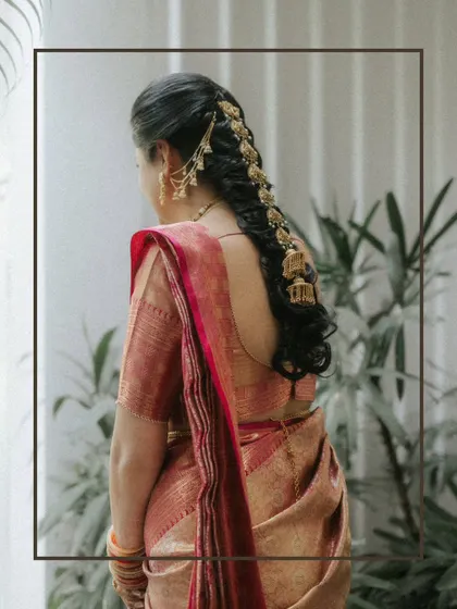 A close-up of the bride's traditional South Indian hairstyle, adorned with beautiful jhumka-style hair accessories.