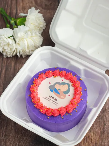 A sweet bento cake for Mother's Day. This purple cake features a cute edible print of a mother and child, surrounded by a border of pink buttercream frosting.