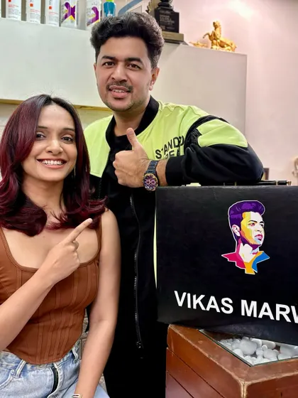 A happy client pointing to her new red-violet hair color. Her smile says it all; a great hair makeover is an instant confidence boost.