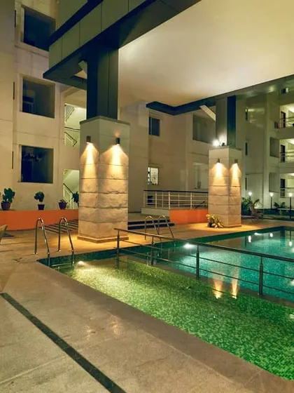 The semi-covered swimming pool at the Unicon Foland apartment complex. The space is designed for all-weather use, with robust columns and ambient lighting creating a relaxing atmosphere.