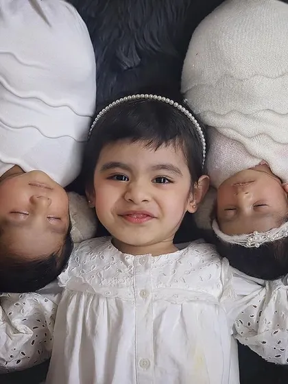 Three souls, one heart. ❤️ An older sister so proud of her new twin siblings. Sibling photos with newborns are so precious, and this overhead shot in classic white is just filled with so much love.