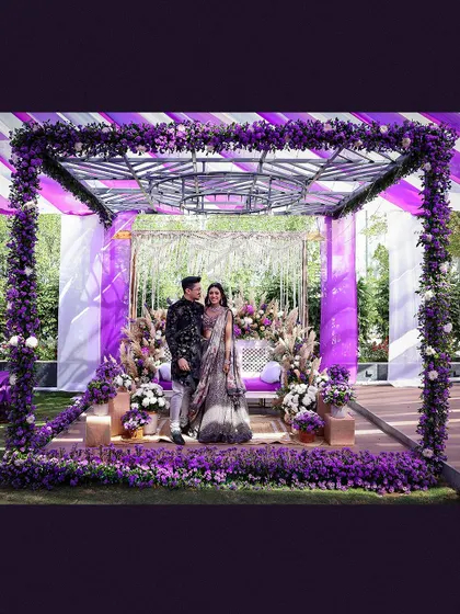 A grand wide shot of the couple standing in their magnificent purple-themed Mehendi venue.