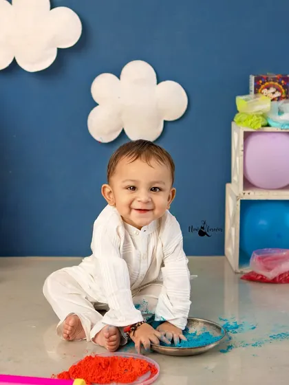 A happy baby boy playing with colorful powders during the Holi mini session.