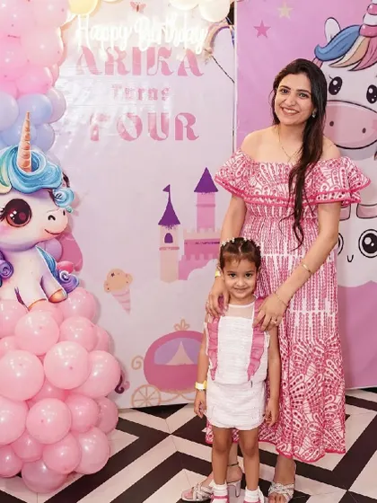 A magical unicorn-themed party setup, featuring a large unicorn backdrop and pink balloon decorations.