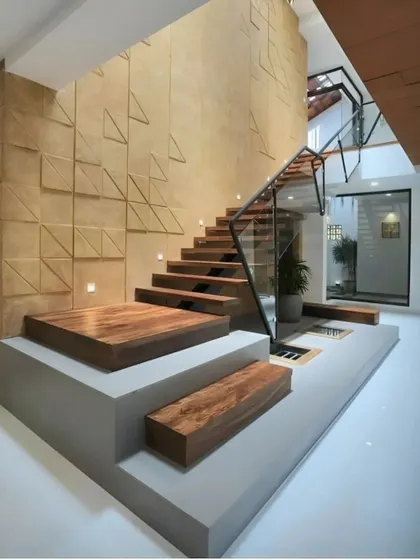 A modern staircase design with floating wooden steps and a glass railing. The textured accent wall with 3D geometric patterns adds a layer of artistic sophistication to the space.