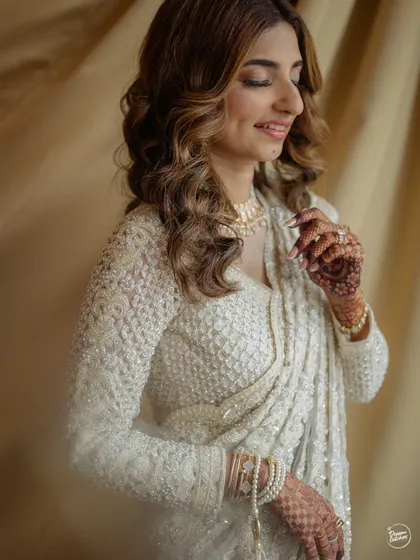A soft and serene portrait of the bride, highlighting the delicate embroidery of her saree and her intricate henna.