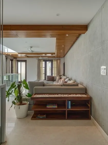 This cozy family space in 'Wilasa' is located on an upper floor, connecting the bedrooms. The material palette of wood, concrete, and soft textiles creates a warm and modern relaxation area.
