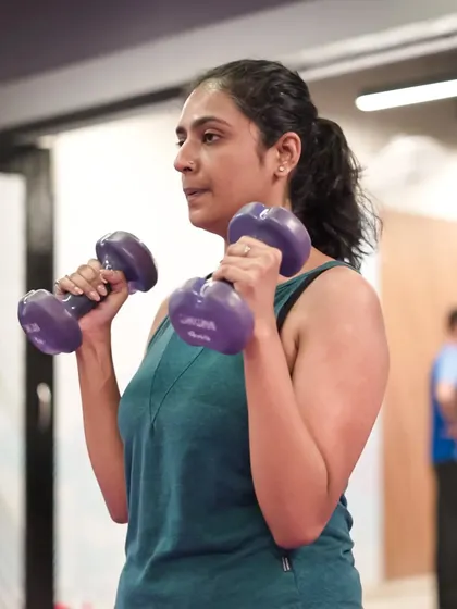 Bicep curls are fundamental for upper arm strength. This client demonstrates proper form using lighter dumbbells, perfect for toning and building endurance.