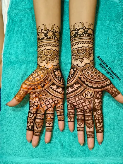 A complete view of a stunning bridal mehndi. Notice how the designs on both hands are unique yet complement each other perfectly, featuring elephants and personalised initials.