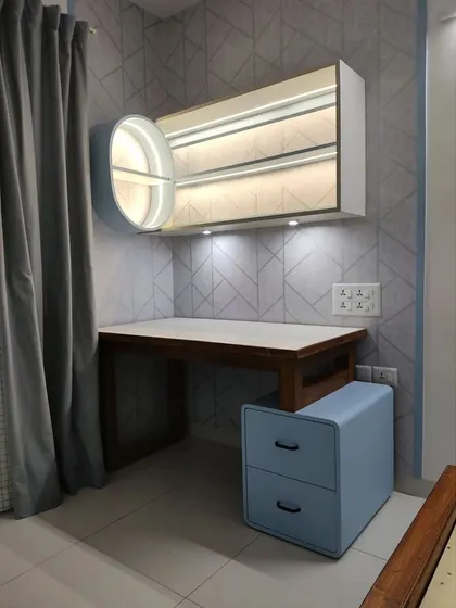 A compact and stylish work-from-home setup integrated into a bedroom. The wall-mounted desk and overhead cabinet with unique circular shelving provide a dedicated workspace without taking up much room.