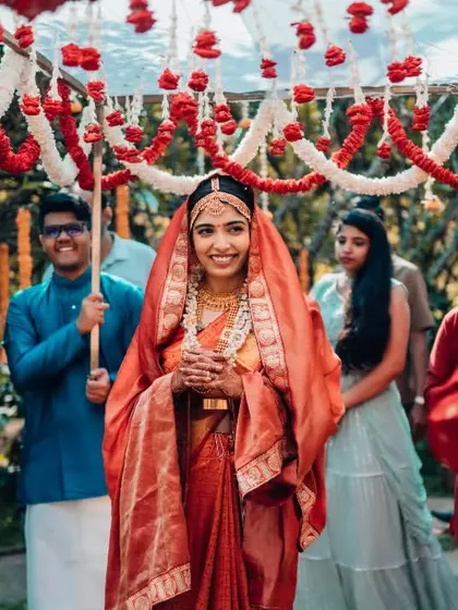 The bride's grand entrance, smiling as she walks under a canopy of flowers held by her brothers.