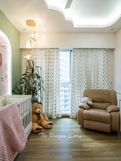 The nursery design includes a low chest of drawers for storage and a comfortable recliner next to the large window. The space is filled with natural light, creating a bright and cheerful atmosphere for the baby.