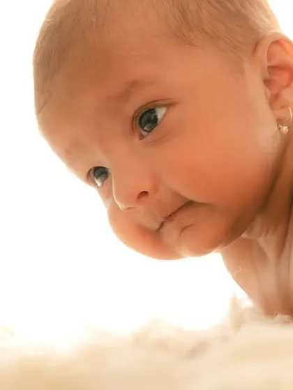 A curious newborn with wide-open eyes during a tummy time pose. It's wonderful to capture these moments of early development.