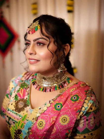 The bride looks radiant and happy in her colorful Haldi outfit. The makeup is fresh and glowing, designed to last through all the fun and festivities.