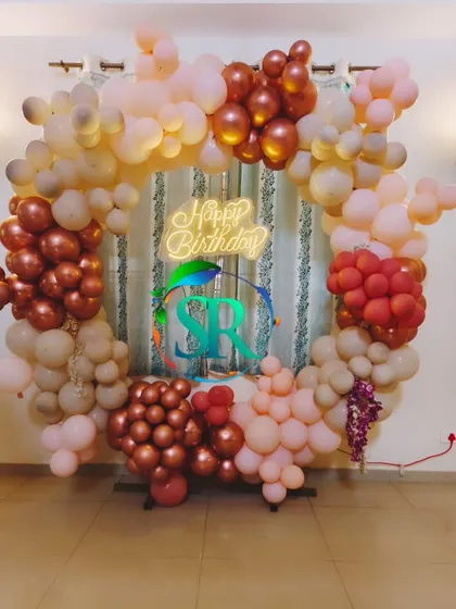 I can create custom color palettes for any celebration. This birthday features a sophisticated balloon arch with rose gold, chrome, and blush tones, complete with a central neon sign.