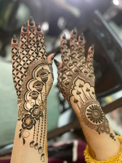 A bold and modern design with a heavy 'jaal' pattern and hanging diya motifs. The other hand features a large, striking mandala.