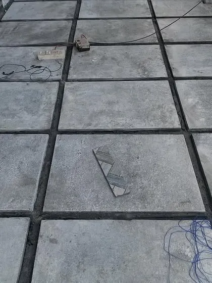 The beginning stages of laying a stone floor. The large concrete pavers are set in place with precise gaps, ready for grouting to create a solid and even surface.