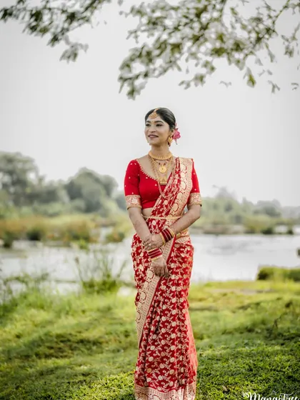 The bride posing gracefully under a tree. Her makeup and hair are styled to look perfect from every angle.