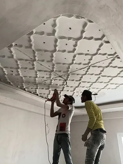A touch of royalty in the making. Our craftsmen are seen here installing a detailed, traditional-style POP ceiling, showcasing their skill and precision.