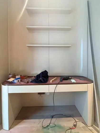 The installation of a custom desk and shelving unit, a glimpse into the finishing stages of a project.