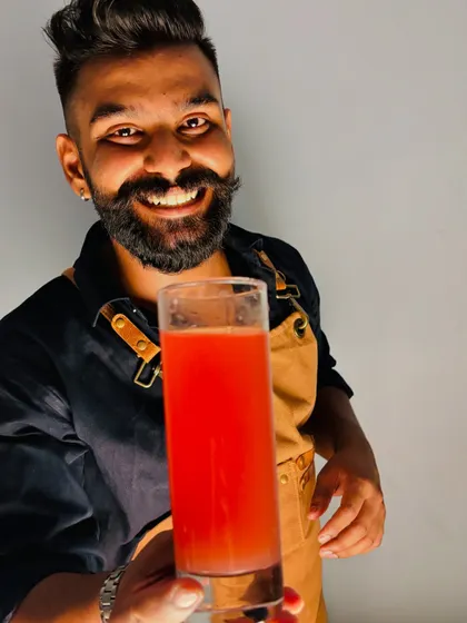 Holding up a freshly made cocktail, crafted with love and precision. This vibrant red drink shows the simple elegance we can bring to your event, whether it's a vodka-based classic or a custom creation.