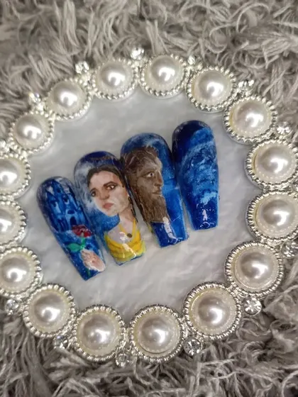 A top-down view of the "Beauty and the Beast" press-on nails, laid out to show the full story across the set.