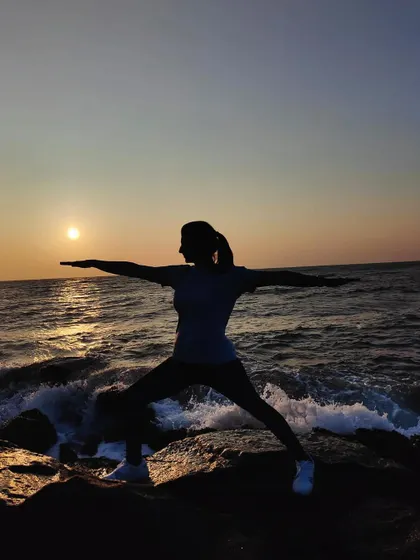 A powerful silhouette of Warrior II pose against the rising sun. A beautiful moment connecting with nature through yoga.