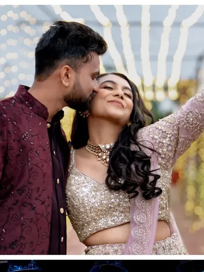 A happy couple enjoying their Sangeet party. The background of cascading fairy lights provides a perfect, sparkling setting for photos.