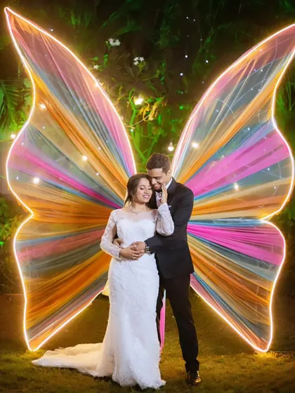 A magical shot in front of giant, colorful butterfly wings. This photo perfectly captures the enchanting and whimsical vibe of their wedding reception.