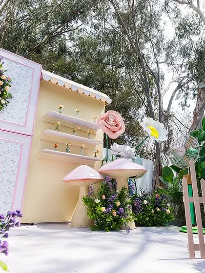A low-angle view of the enchanting flower garden stage, showcasing the depth and layers of the design. From the purple flowers in the foreground to the whimsical backdrop, every element is carefully placed.