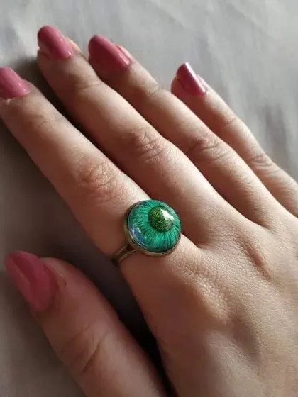 This ethnic ring features a vibrant green flower preserved in resin. The simple, adjustable band makes it easy to wear, adding a pop of color to your look.