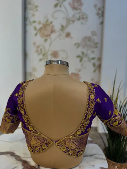 The back of the purple blouse, featuring a unique V-shaped cut-out design with embroidered borders.