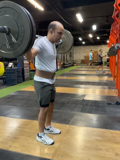 An athlete demonstrating the starting position for a drop snatch, with the bar on his back. From here, the goal is to drop into a full overhead squat as quickly as possible.