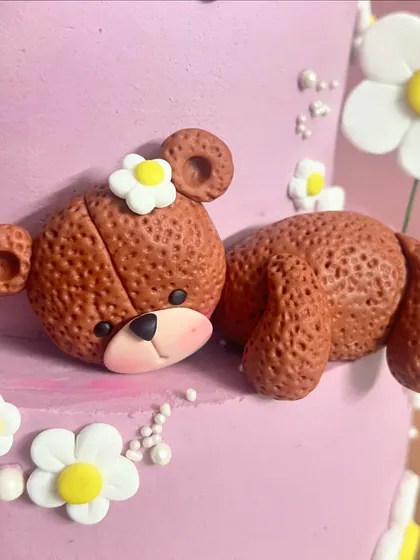 Even the sleeping bears are cute. This little fondant teddy peeking out from the side of the cake adds a playful and sweet element to the overall teddy and daisy theme.