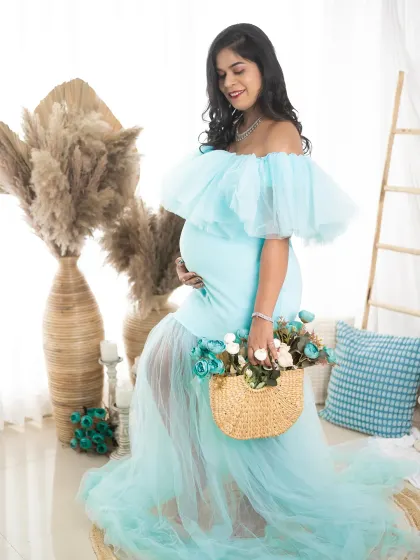 A dreamy and delicate portrait of a mom-to-be in a light blue gown. The soft lighting and thoughtful pose capture the wonder of this special time.