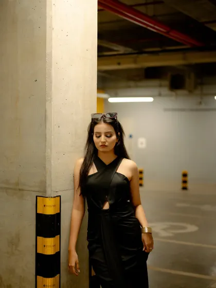A moody and atmospheric shot taken inside a parking garage. The industrial setting and the model's pose create an edgy and modern fashion portrait.