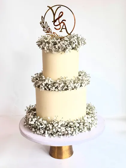 A full view of the two-tier baby's breath anniversary cake, complete with a custom initial topper.