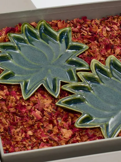 Two of our green lotus trinket plates nestled in a gift box filled with fragrant dried rose petals. We take great care in our packaging to ensure the unboxing experience feels truly special.