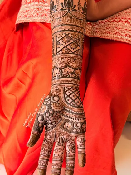 A close-up of the intricate patterns on the palm and forearm of a Rajasthani bridal design, featuring lotus motifs and geometric fills.