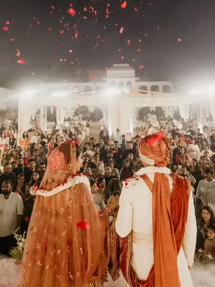 The couple standing before their guests during the ceremony. The shower of rose petals from above creates a beautiful and blessed moment.