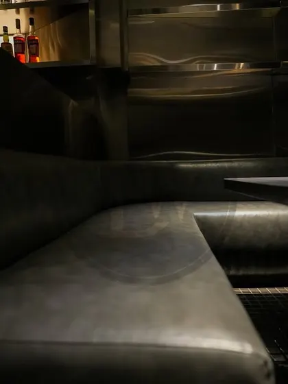 The sleek, dark leatherette upholstery on the banquette seating at Call Me Ten, complete with under-seat lighting for a dramatic effect. This material is perfect for high-traffic restaurant use.