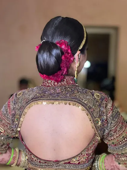 This is a very sleek and traditional bridal bun, also known as a juddha. I wrapped it with a string of pink flowers to match the bride's ornate lehenga.