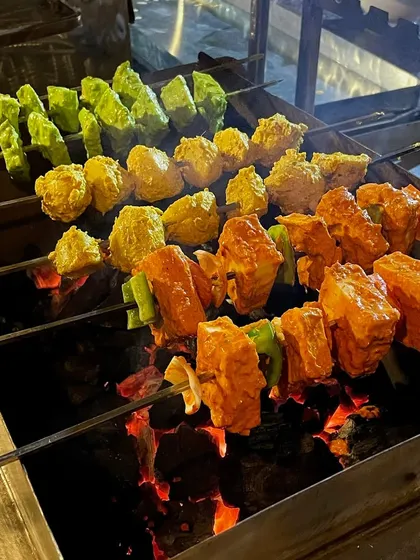 A close-up of paneer and vegetable skewers grilling over the charcoal. The direct heat gives them a perfect char and an unbeatable smoky flavor that you can't get from a standard oven.